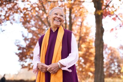 Nikki Giovanni stands on campus with fall colors