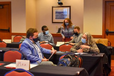 A group of five faculty members gathered at tables as part of a workshop for the Conference on Higher Education Pedagogy.