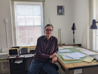 John Ambrose sitting at his work desk in his office