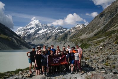 A group of people stand in front of a snow-capped mountain.