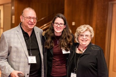 A man poses with two women, one if whom is a an alumna of the university.